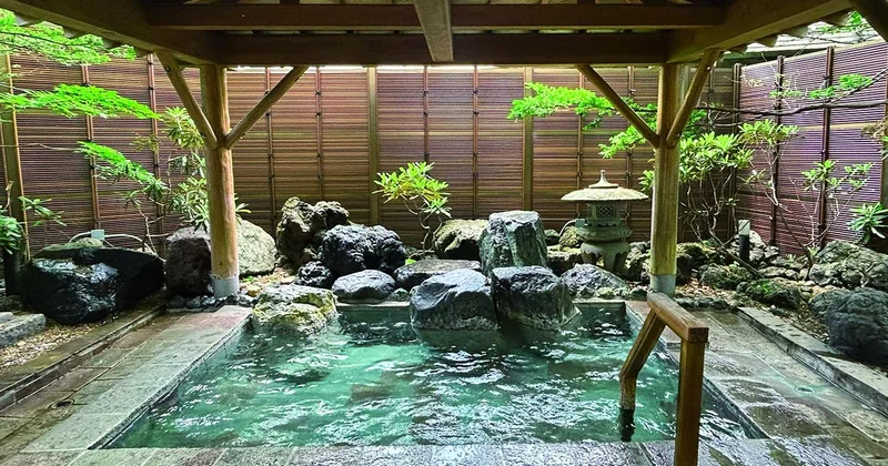 草津温泉の岩に囲まれた屋根付き露天風呂と湯船