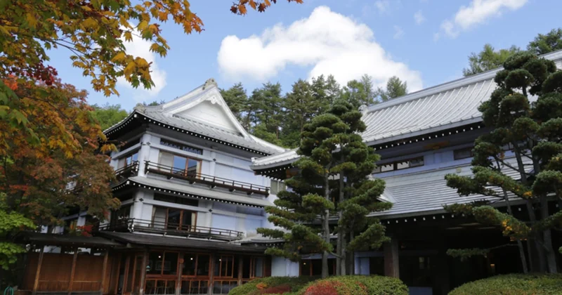 草津温泉の紅葉に囲まれた伝統的な和風旅館の外観と庭園
